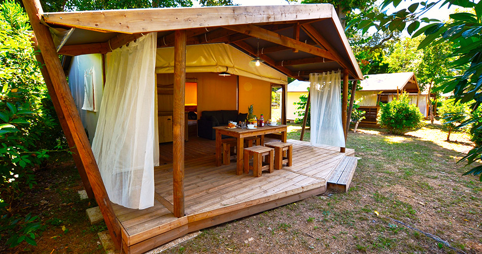 Abri de camping en bois dans un jardin serein, idéal pour des vacances confortables en pleine nature.