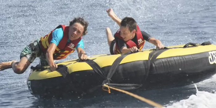 Cette image dynamique de tubing montre deux amis s'éclatant sur l'eau, symbolisant l'essence même de l'été. Leur joie est palpable, créant un tableau d'amitié et d'activités excitantes qui ravira les amateurs de sensations fortes.