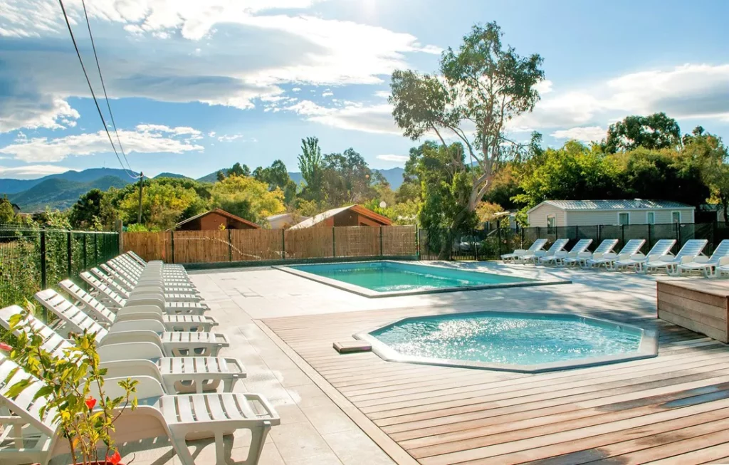 camping-kalliste-saint-florent-piscine Espace piscine moderne du camping Kalliste à Saint-Florent avec transats et vue sur les montagnes.