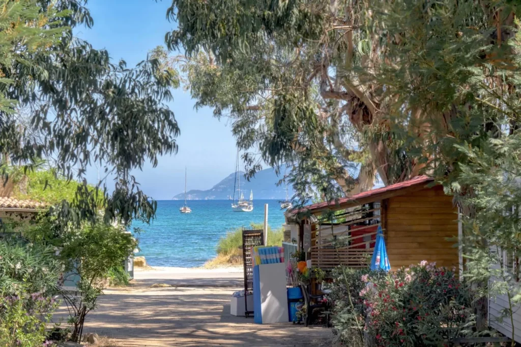 camping-u-pezzo-vue-mer-saint-florent Allée fleurie du camping U Pezzo avec vue sur les voiliers ancrés dans le golfe de Saint-Florent.