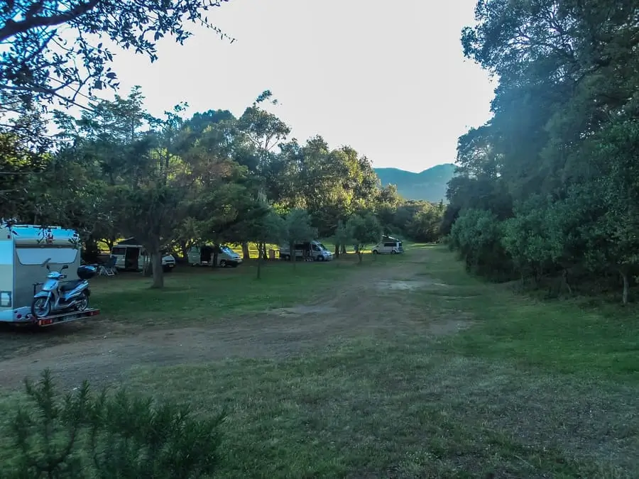 camping-u-stazzu-vue-montagne-corse Caravanes et vans installés sur une vaste étendue herbeuse au camping U Stazzu face aux montagnes corses.